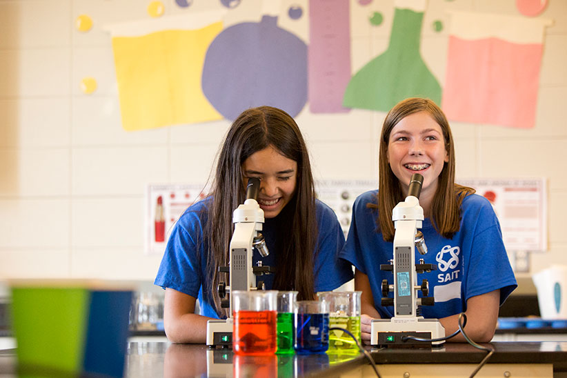 Two girls smiling with microscopes
