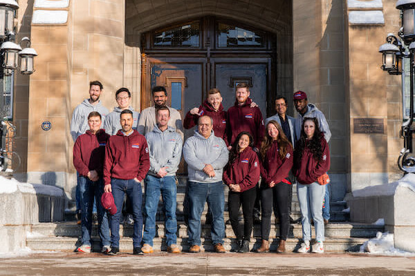 Group photo of a diverse team of individuals wearing maroon and gray attire