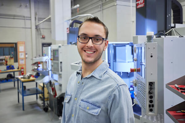 A student wearing safety classes smiles at the camera